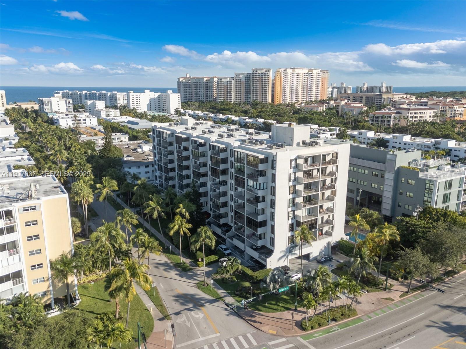 An aerial view shows a white multi-story apartment building surrounded by palm trees and roads — 575 Crandon Blvd # 504, Key Biscayne FL 33149, KEY BISCAYNE, FL