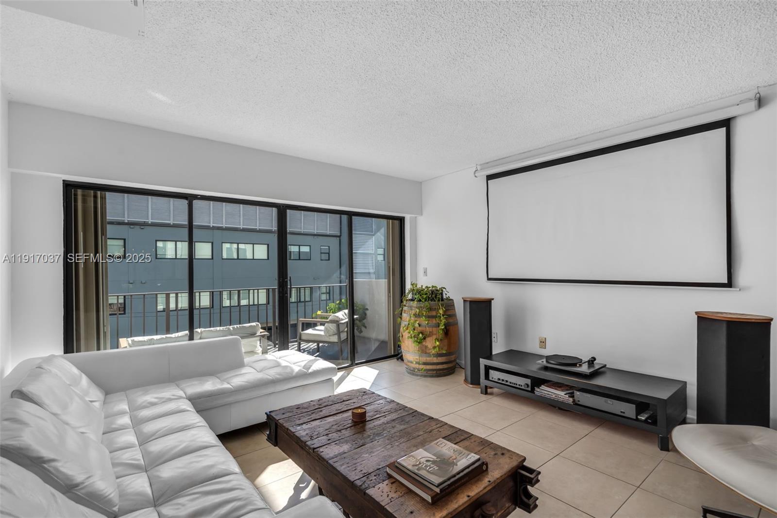 A living room features a white sectional sofa, a wooden coffee table, and a projector screen — 575 Crandon Blvd # 504, Key Biscayne FL 33149, KEY BISCAYNE, FL