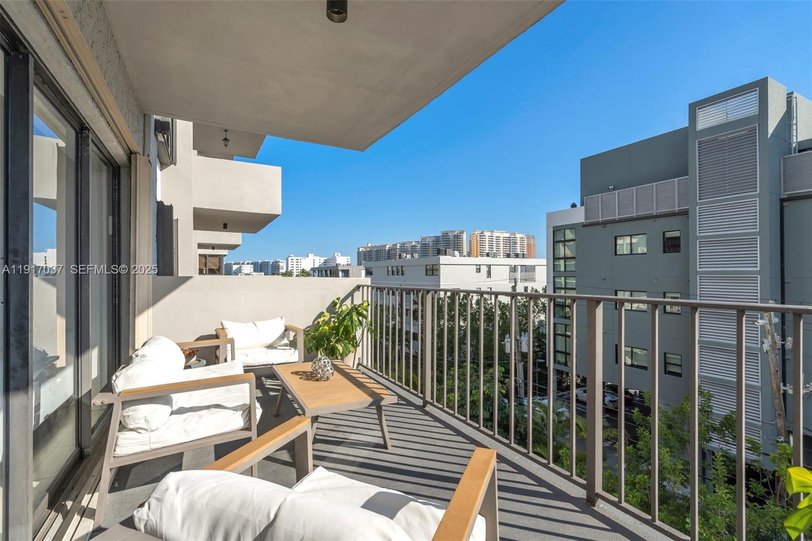 A balcony features outdoor seating, a small table, and a metal railing overlooking city buildings — 575 Crandon Blvd # 504, Key Biscayne FL 33149, KEY BISCAYNE, FL
