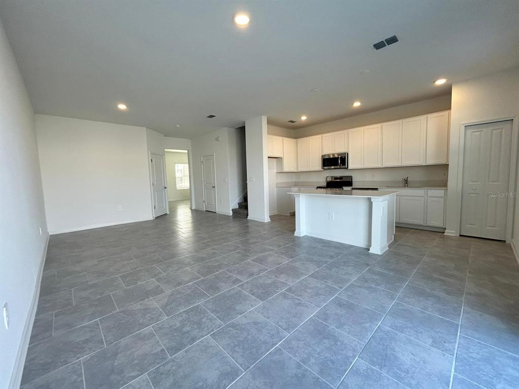 An open-concept kitchen and living area features white cabinetry, a center island, and tile flooring — 3019 CHANTILLY DRIVE, DAVENPORT, FL