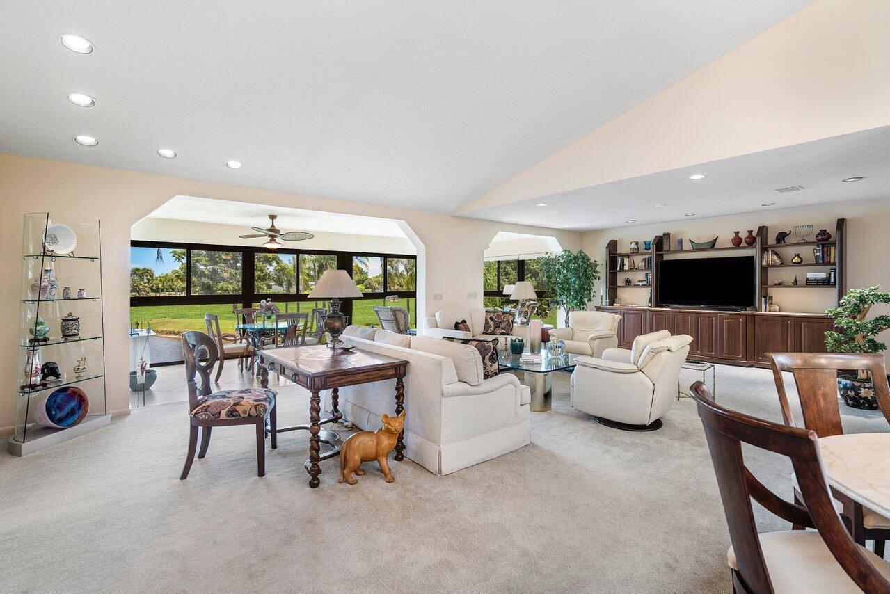 A spacious living room features a large entertainment center, neutral furniture, and a view outdoors — 69 Eastgate Drive Unit D, Boynton Beach FL 33436, BOYNTON BEACH, FL