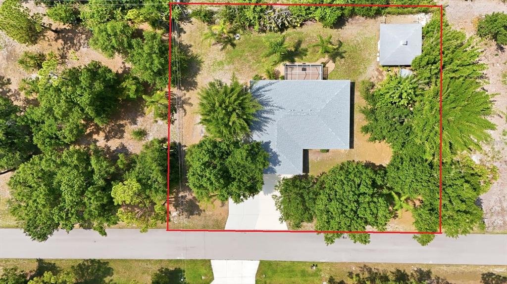 An aerial view shows a house with a gray roof, a detached shed, and trees — 22481 MADELYN AVENUE, PORT CHARLOTTE, FL
