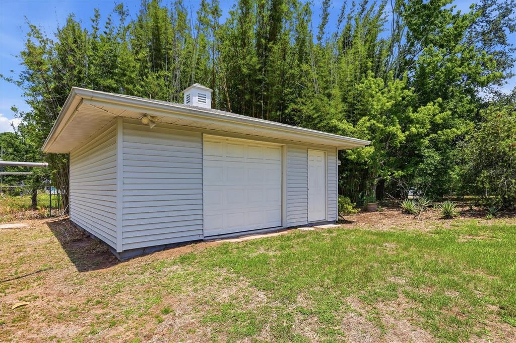 A detached garage with light-colored siding, a white roll-up door, and a small cupola — 22481 MADELYN AVENUE, PORT CHARLOTTE, FL