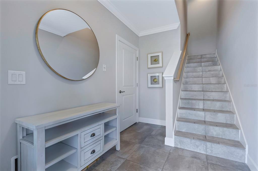 A tiled entryway features a white console table, a round mirror, and stairs leading upward — 4063 ROCKY SHORES DRIVE, TAMPA, FL