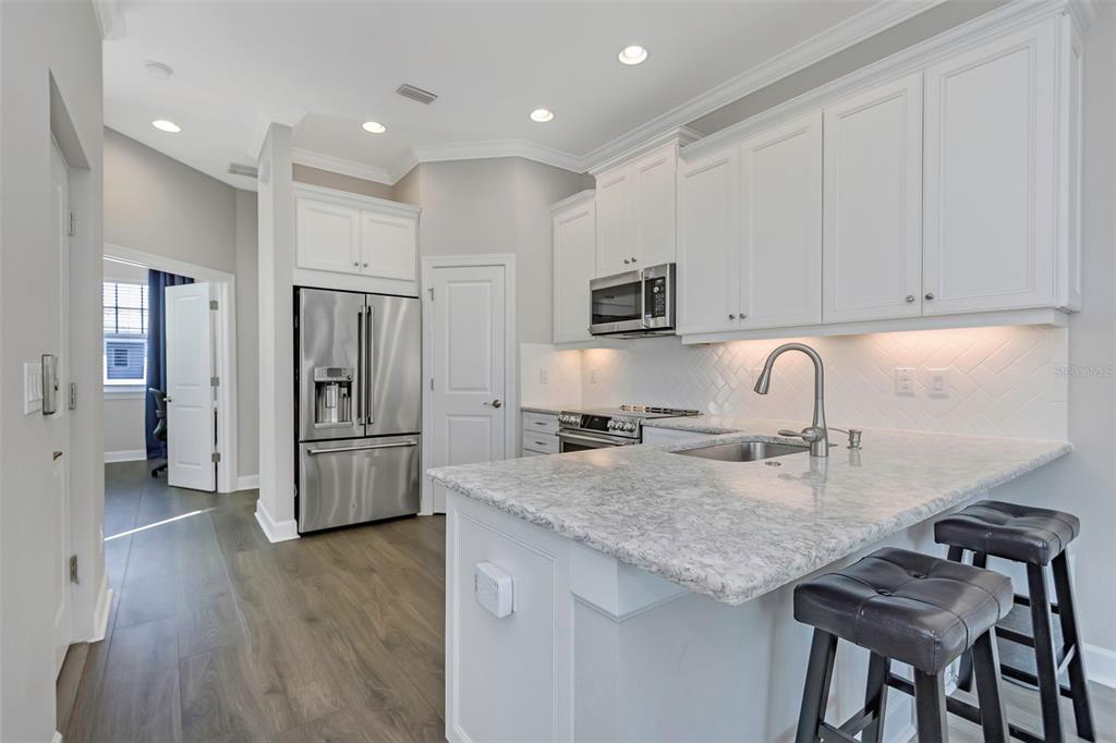 A modern kitchen features white cabinets, stainless steel appliances, and a granite-topped breakfast bar — 4063 ROCKY SHORES DRIVE, TAMPA, FL