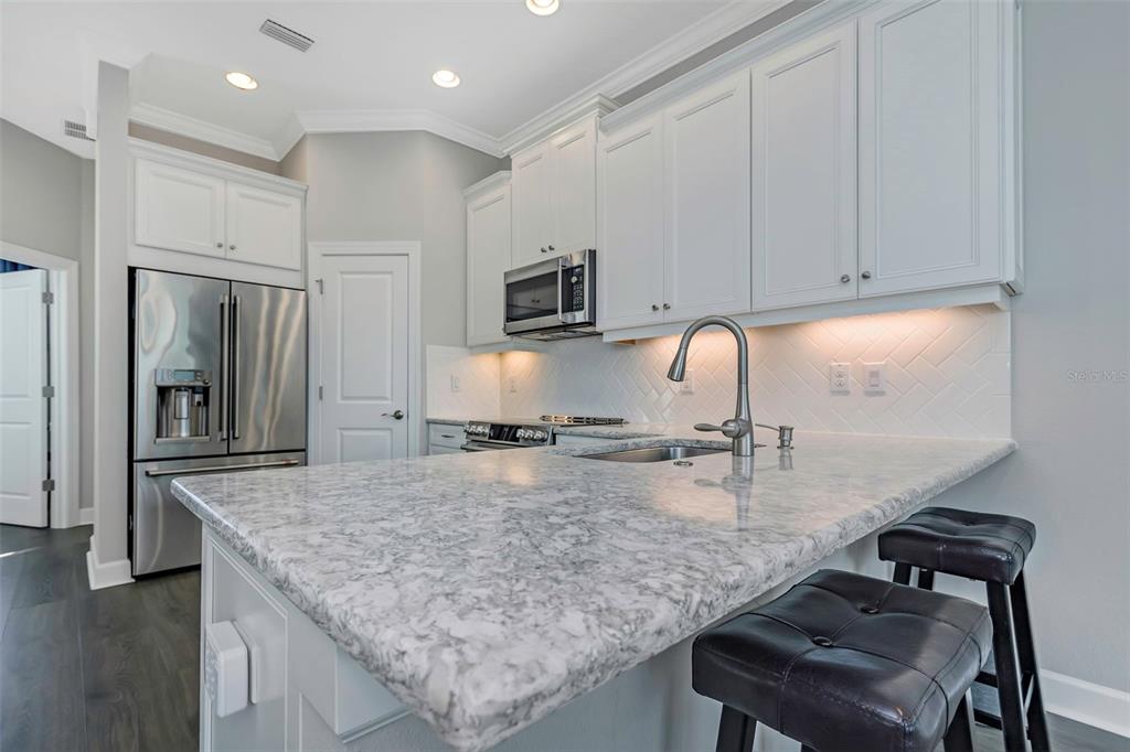 A kitchen features white cabinets, a marble-patterned island countertop, and stainless steel appliances — 4063 ROCKY SHORES DRIVE, TAMPA, FL