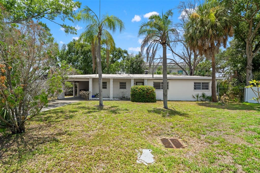 A single-story house with a carport, white brick facade, and palm trees in the yard — 4635 W BAY VILLA AVENUE, TAMPA, FL