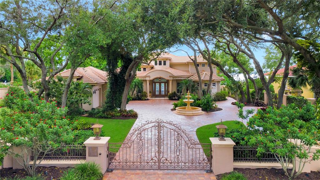 A large two-story house with a gated driveway, a central fountain, and mature oak trees — 416 81ST STREET W, BRADENTON, FL