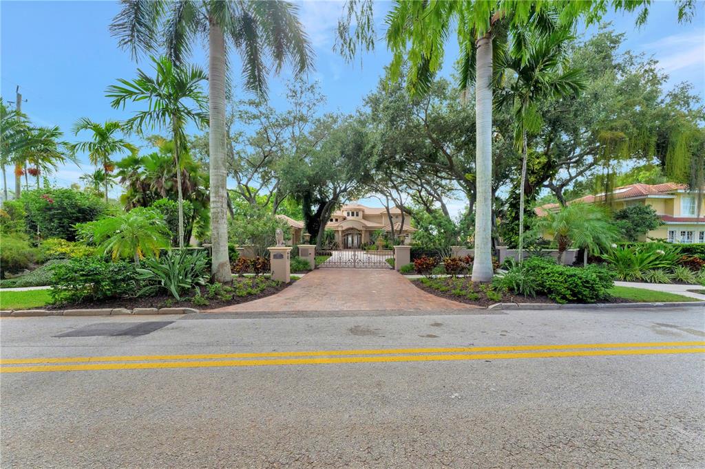 A gated driveway leads to a large house surrounded by mature trees and palm trees — 416 81ST STREET W, BRADENTON, FL