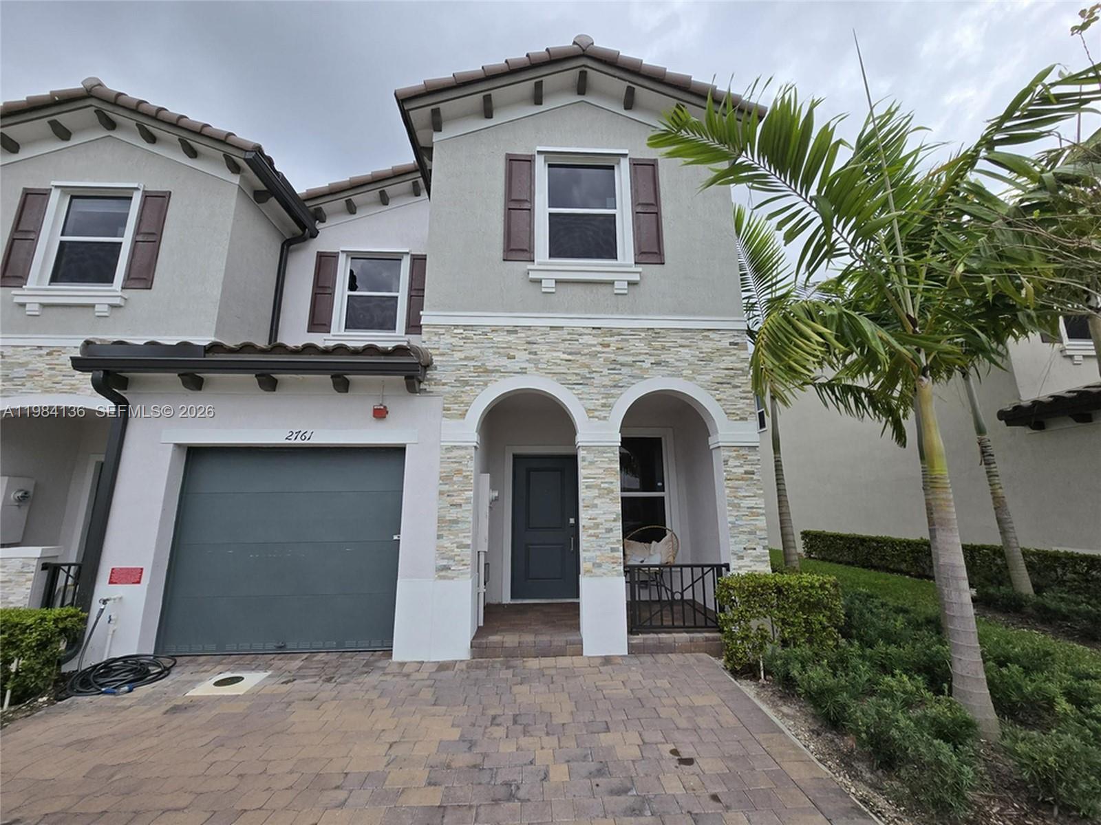 A two-story townhouse features a stone-accented facade, arched entryway, and a paved driveway — 2761 NW 55th Way, Lauderhill FL 33313, LAUDERHILL, FL