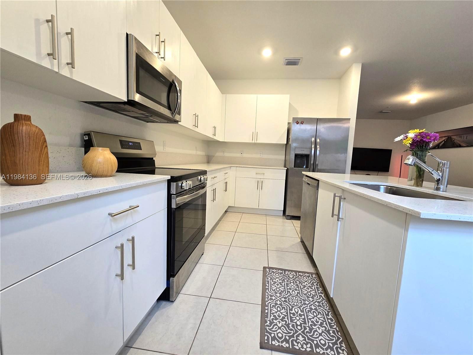 A modern kitchen features white cabinets, stainless steel appliances, and light-colored countertops — 2761 NW 55th Way, Lauderhill FL 33313, LAUDERHILL, FL
