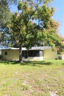 A single-story yellow house with a screened porch sits behind a large tree — 905 MARION DRIVE, MOUNT DORA, FL