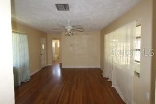 An interior view of a room with hardwood floors, a ceiling fan, and white curtains — 905 MARION DRIVE, MOUNT DORA, FL