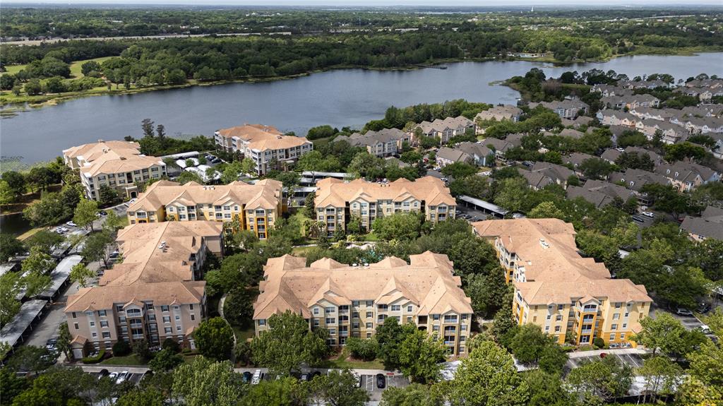 An aerial view shows several multi-story apartment buildings situated near a large lake — 3326 ROBERT TRENT JONES DRIVE UNIT 30102, ORLANDO, FL