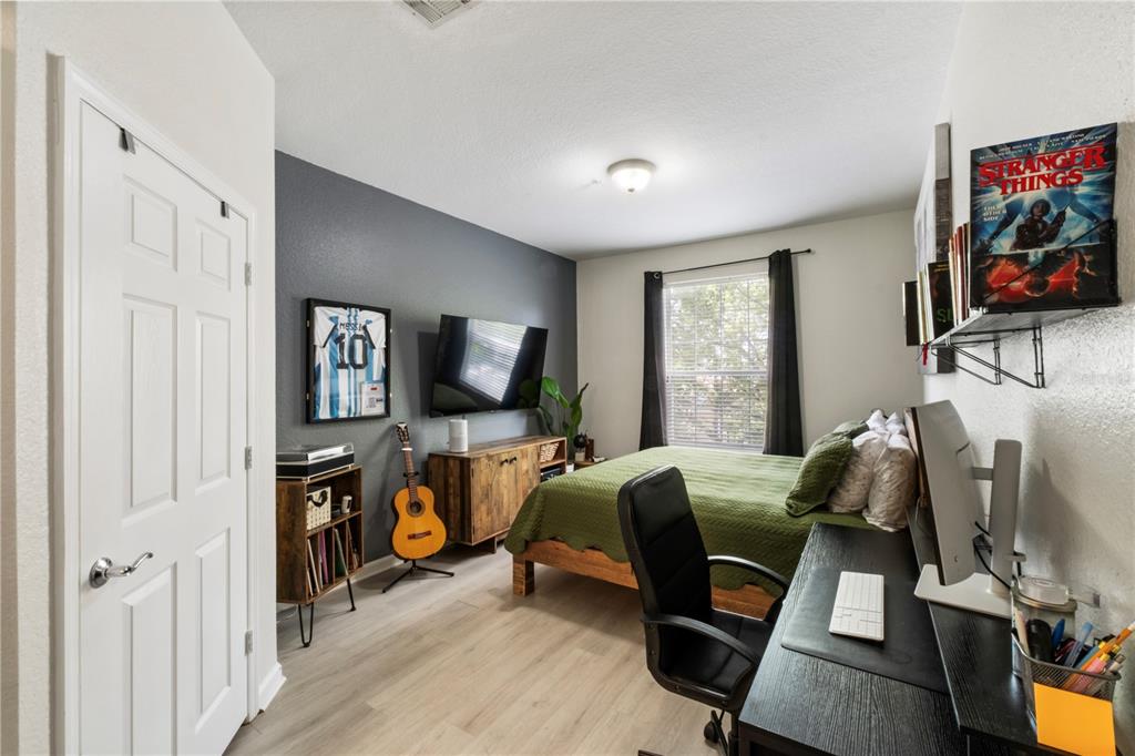 A bedroom features a bed, a desk, a television, and a framed soccer jersey — 3326 ROBERT TRENT JONES DRIVE UNIT 30102, ORLANDO, FL