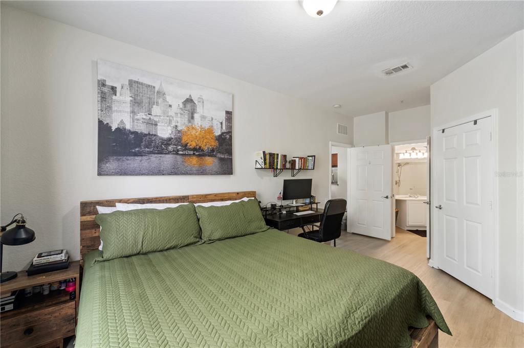 A bedroom features a green quilt, a wooden headboard, a desk, and an attached bathroom — 3326 ROBERT TRENT JONES DRIVE UNIT 30102, ORLANDO, FL