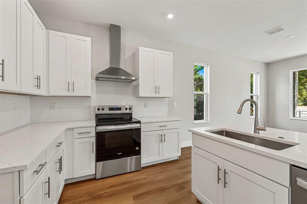 A modern kitchen features white cabinets, stainless steel appliances, and a central island with sink — 1005 W CYPRESS STREET UNIT 1, TAMPA, FL