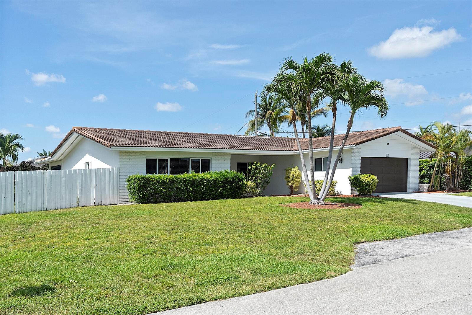 A single-story white house with a brown roof, a garage, and palm trees — 2910 NE 40th Court, Lighthouse Point FL 33064, LIGHTHOUSE POINT, FL