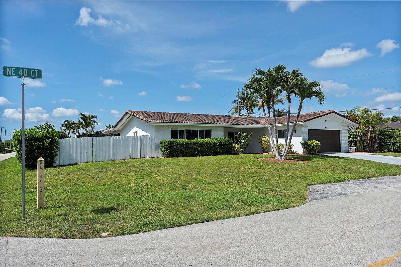 A single-story house with a white exterior, brown roof, and palm trees in the yard — 2910 NE 40th Court, Lighthouse Point FL 33064, LIGHTHOUSE POINT, FL