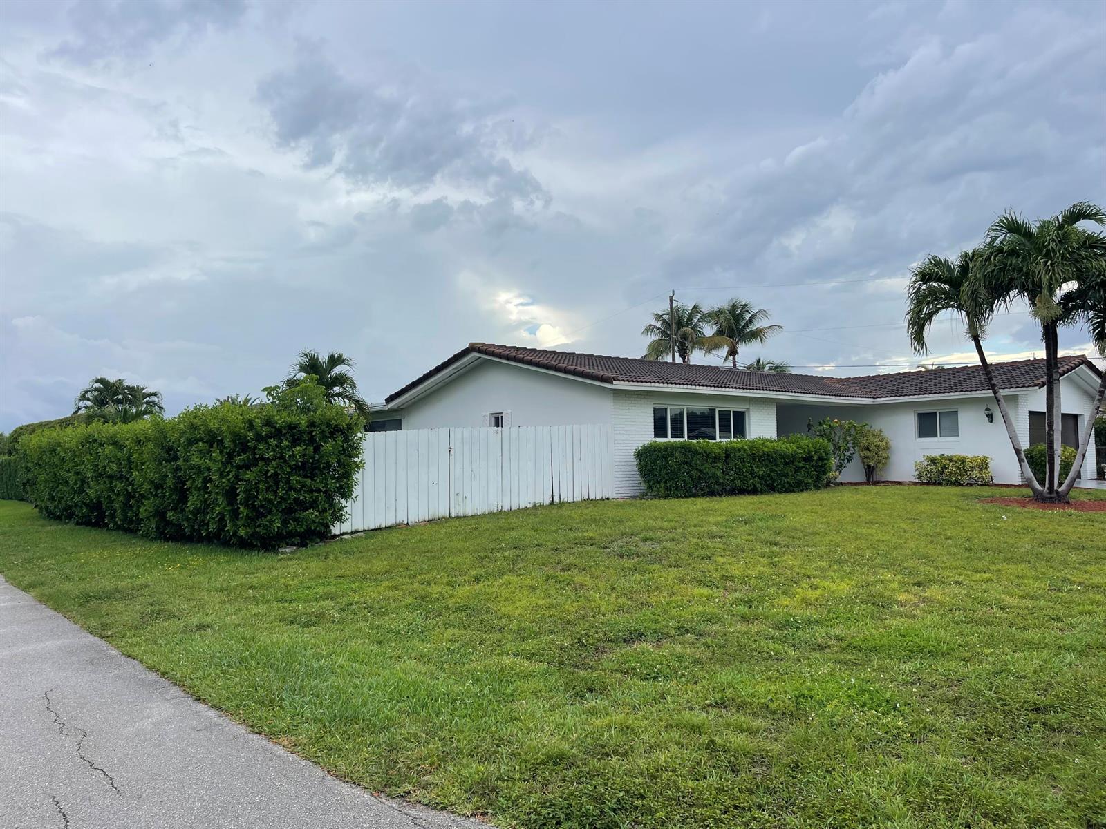 A white single-story house with a brown tile roof sits behind a green lawn — 2910 NE 40th Court, Lighthouse Point FL 33064, LIGHTHOUSE POINT, FL