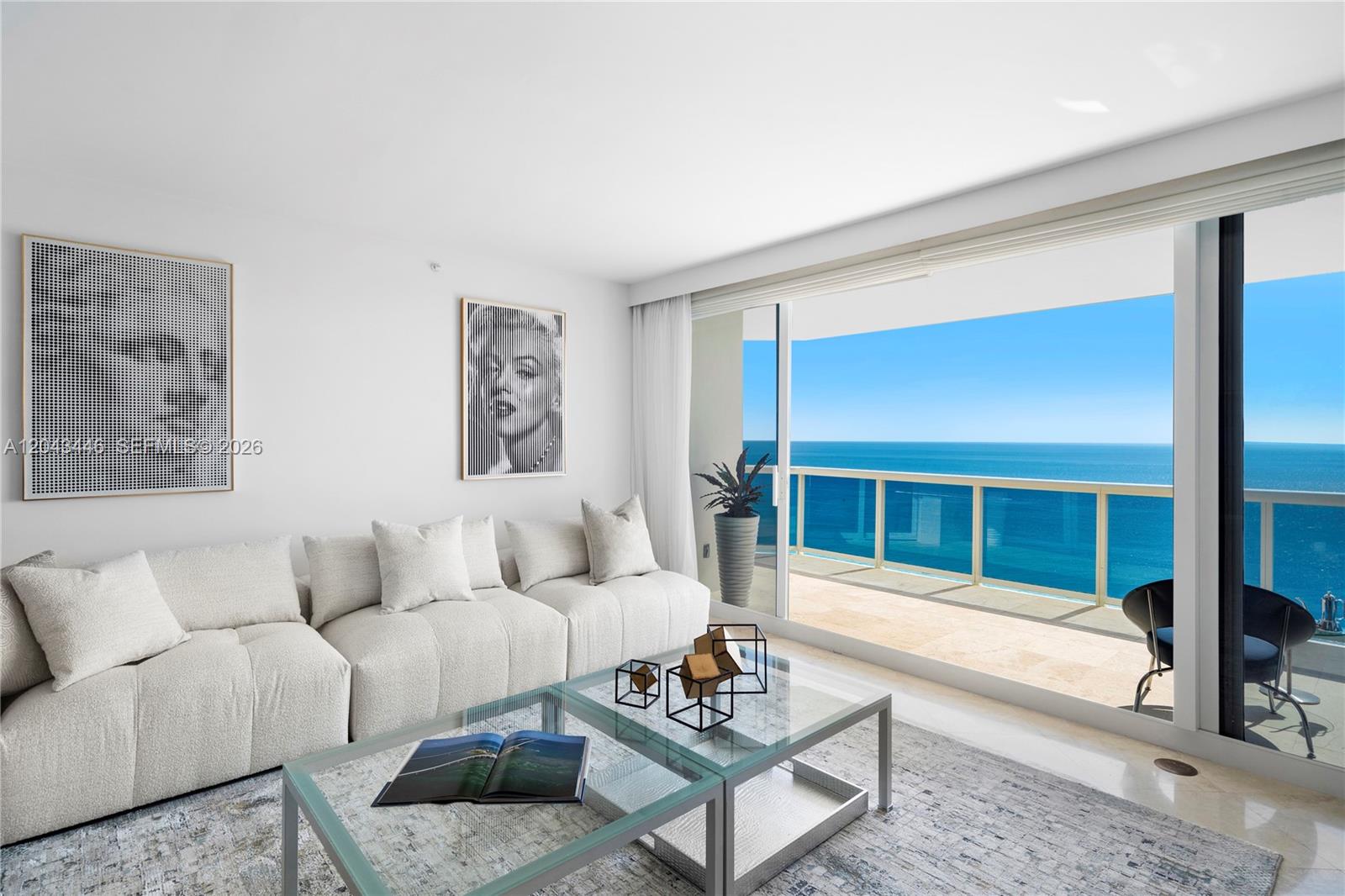A modern living room features a white sectional sofa, glass coffee tables, and a balcony view — 4779 Collins Ave, Miami Beach FL 33140, MIAMI BEACH, FL