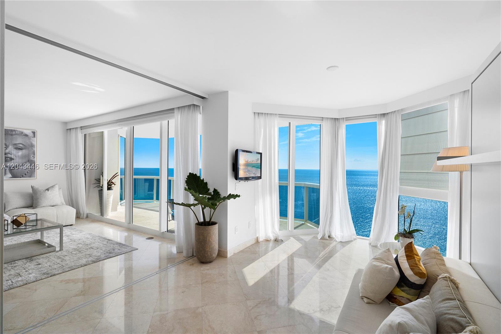 A bright living room features marble floors, floor-to-ceiling windows, and panoramic ocean views — 4779 Collins Ave, Miami Beach FL 33140, MIAMI BEACH, FL