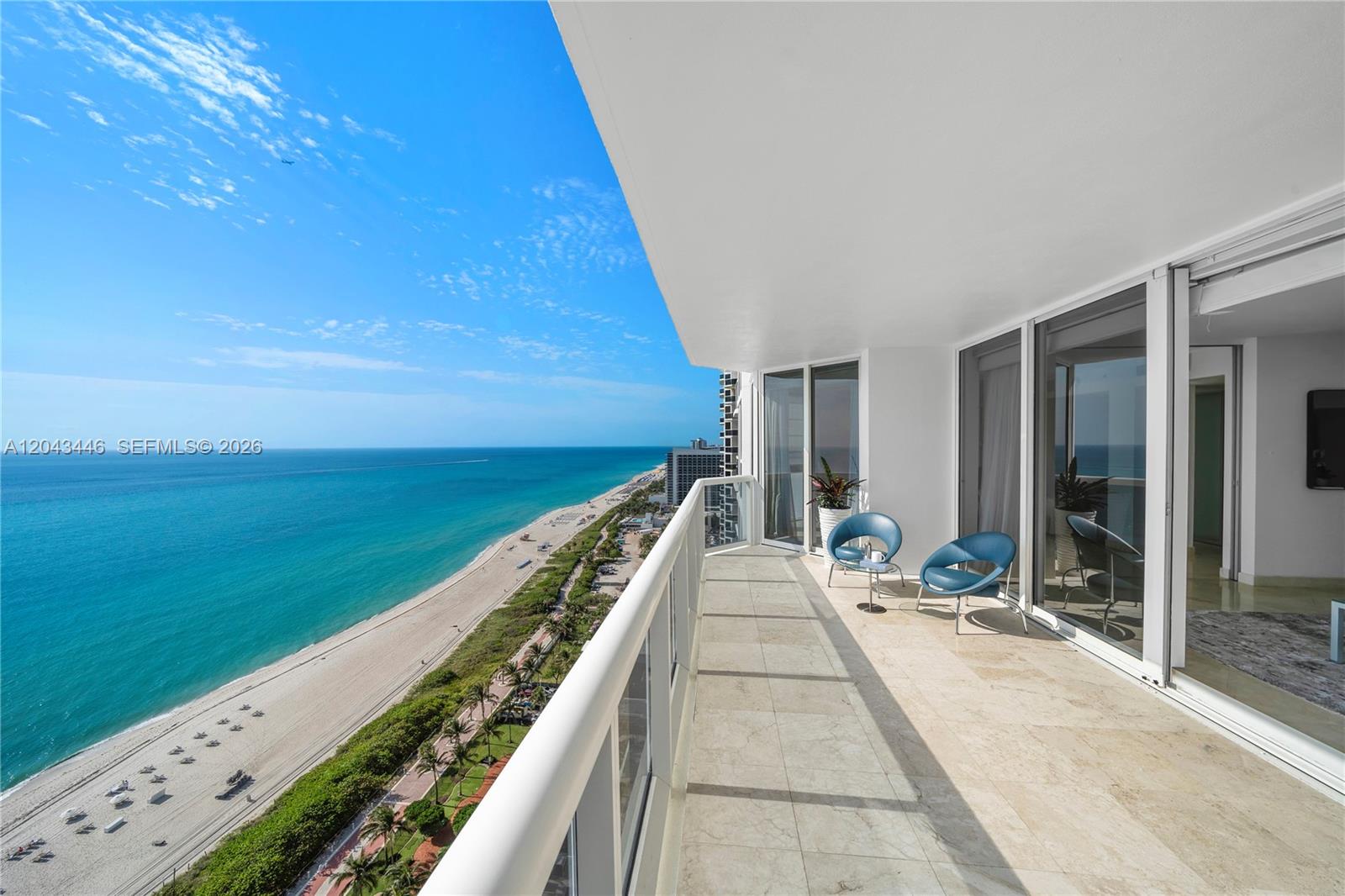 A balcony with stone flooring and two blue chairs overlooks a beach and ocean — 4779 Collins Ave, Miami Beach FL 33140, MIAMI BEACH, FL
