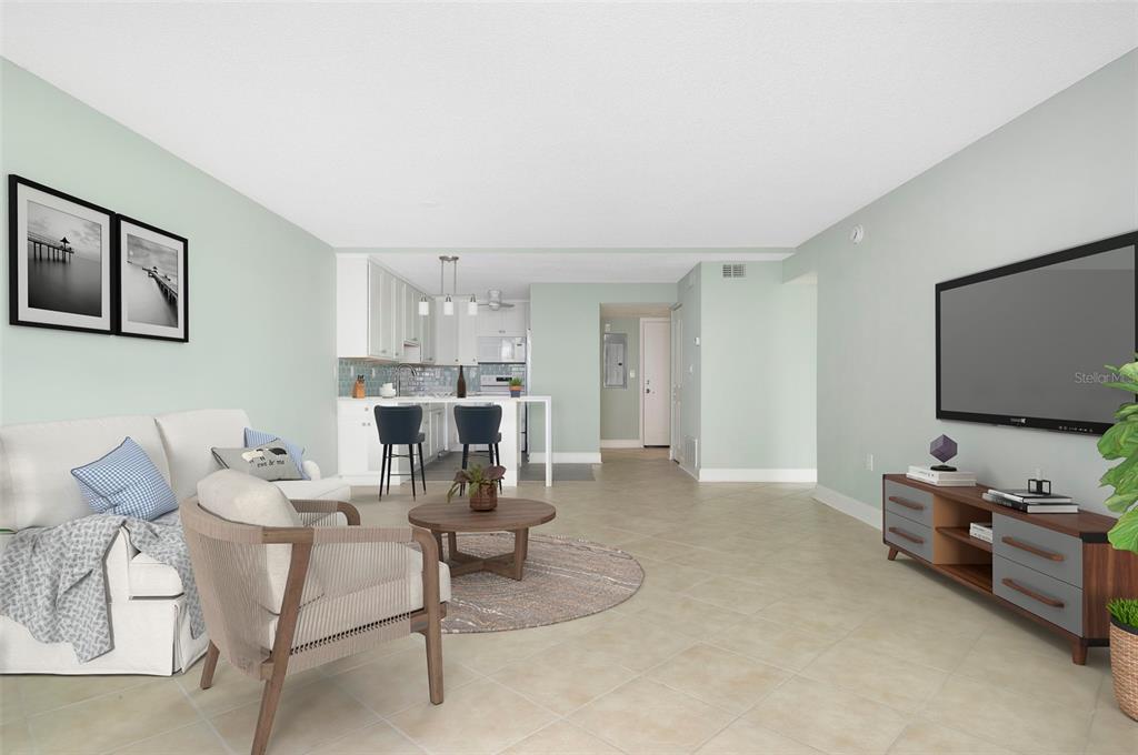 A living room with light green walls, tile flooring, a white sofa, and an open kitchen — 450 TREASURE ISLAND CAUSEWAY UNIT 105, TREASURE ISLAND, FL