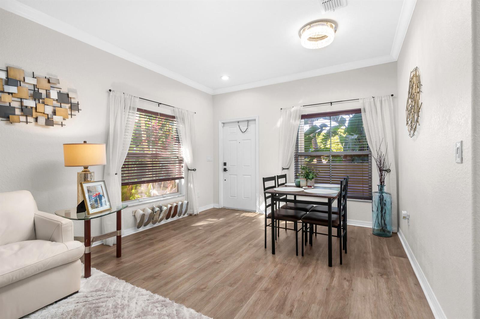 A dining area with wood-look flooring, a white front door, and two windows with curtains — 155 Monterey Bay Drive, Boynton Beach FL 33426, BOYNTON BEACH, FL