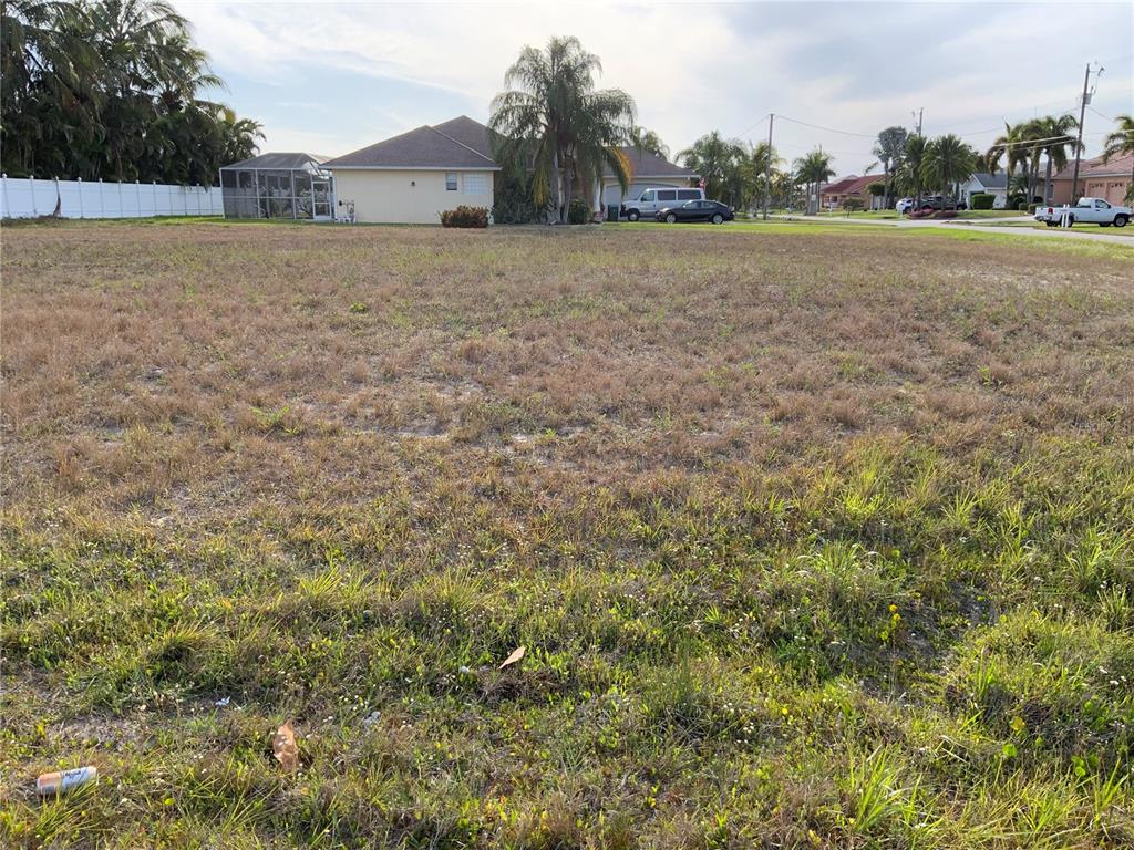 A vacant, grassy residential lot sits in front of a suburban house and street — 2000 SW 28TH TERRACE, CAPE CORAL, FL