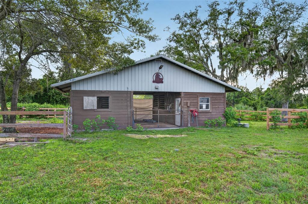 A brown wooden barn with a metal roof stands in a grassy, fenced-in pasture — 1690 TALLAPOOSA DRIVE, GENEVA, FL