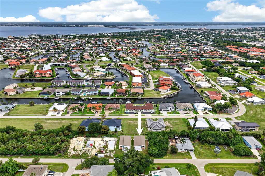 An aerial view shows a residential neighborhood with a white arrow pointing to a house — 1018 S MARLIN DRIVE, PUNTA GORDA, FL