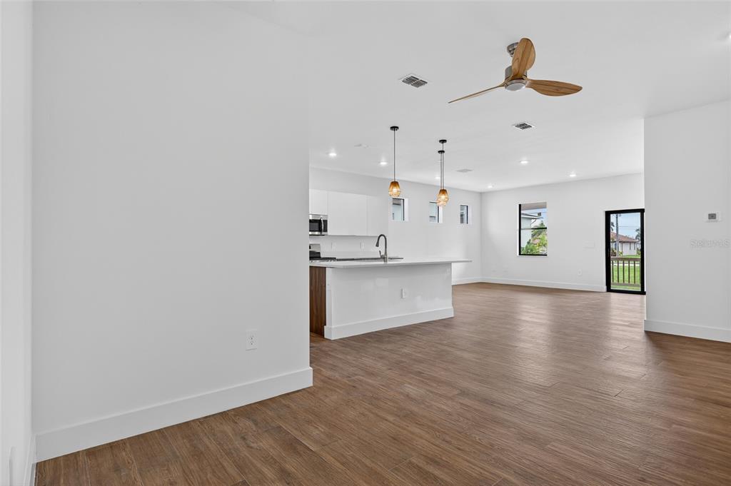 An open-concept kitchen and living area features white cabinetry, a kitchen island, and wood-look flooring — 1018 S MARLIN DRIVE, PUNTA GORDA, FL
