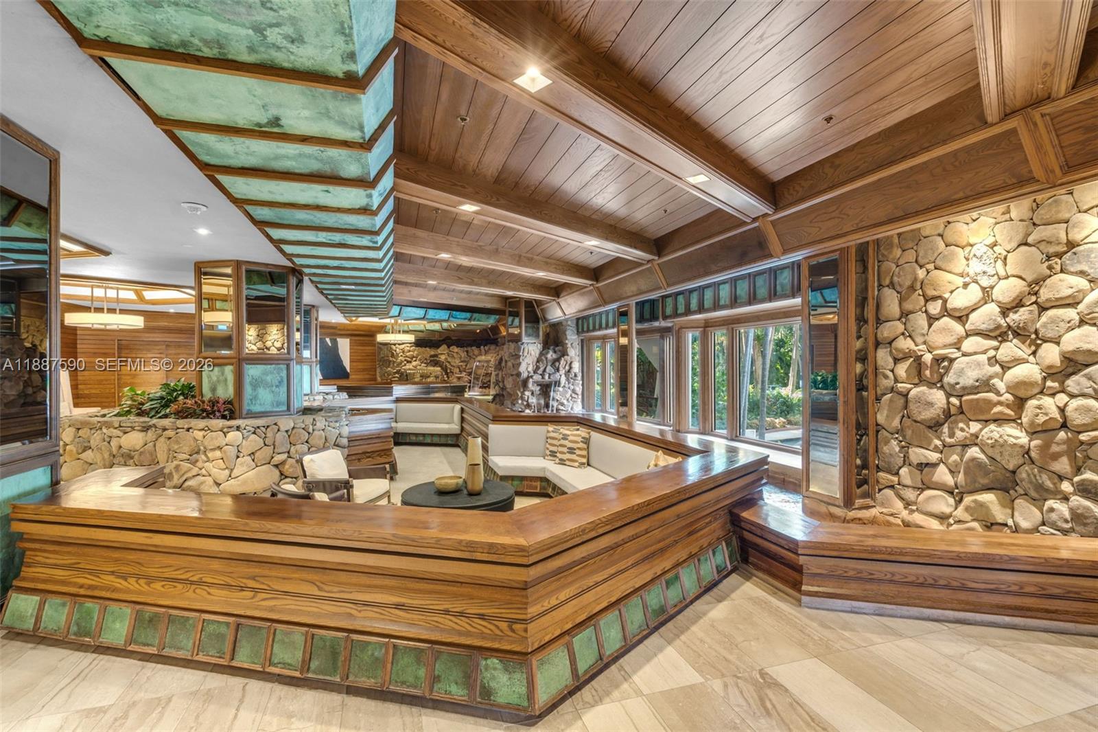 A sunken living room features wood-paneled ceilings, stone walls, and a built-in wooden seating area — 1000 Quayside Ter # 505, Miami FL 33138, MIAMI, FL