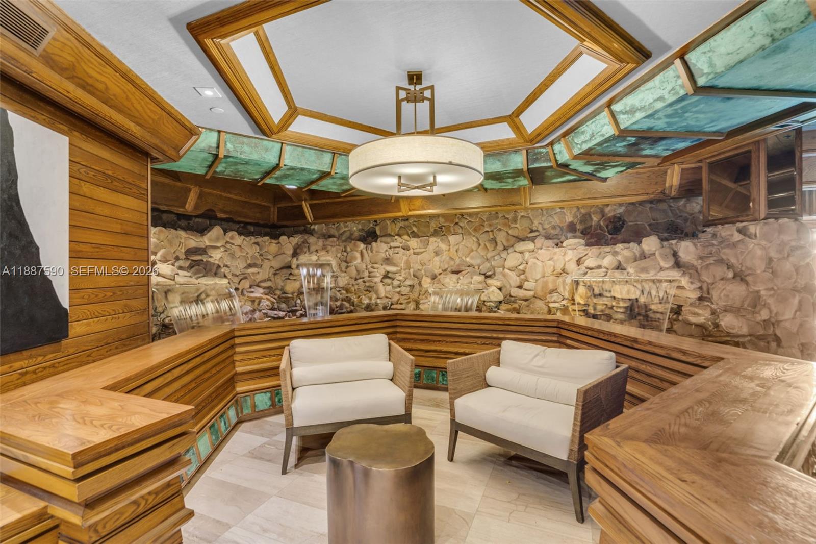 A lounge area features a stone wall with water features, wood paneling, and a chandelier — 1000 Quayside Ter # 505, Miami FL 33138, MIAMI, FL
