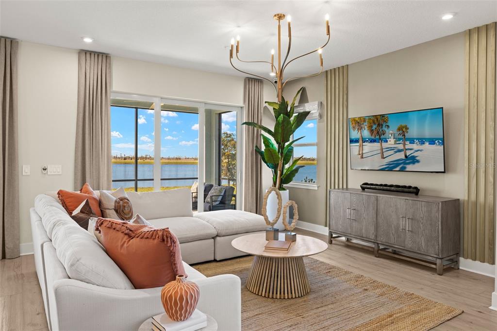 A living room features a white sectional sofa, a wooden coffee table, and a lake view — 12829 JADE EMPRESS LOOP UNIT 101, VENICE, FL