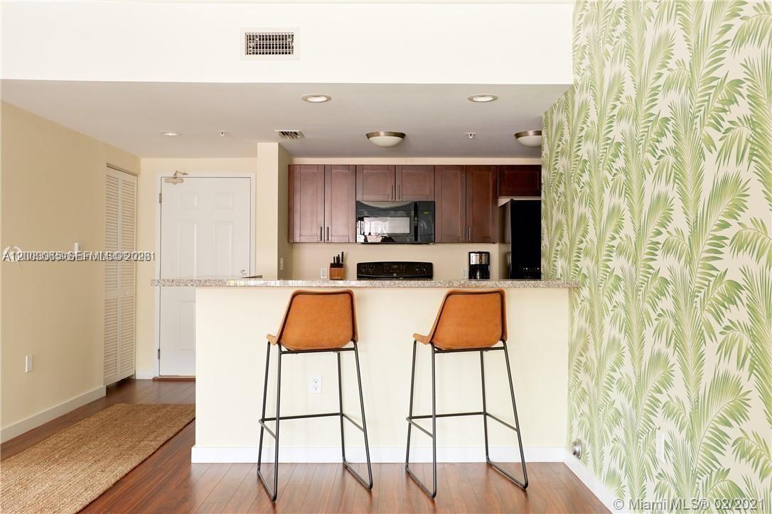 A living room features a yellow sofa, a glass coffee table, and palm-patterned wallpaper — 568 NE 66th St # 501, Miami FL 33138, MIAMI, FL