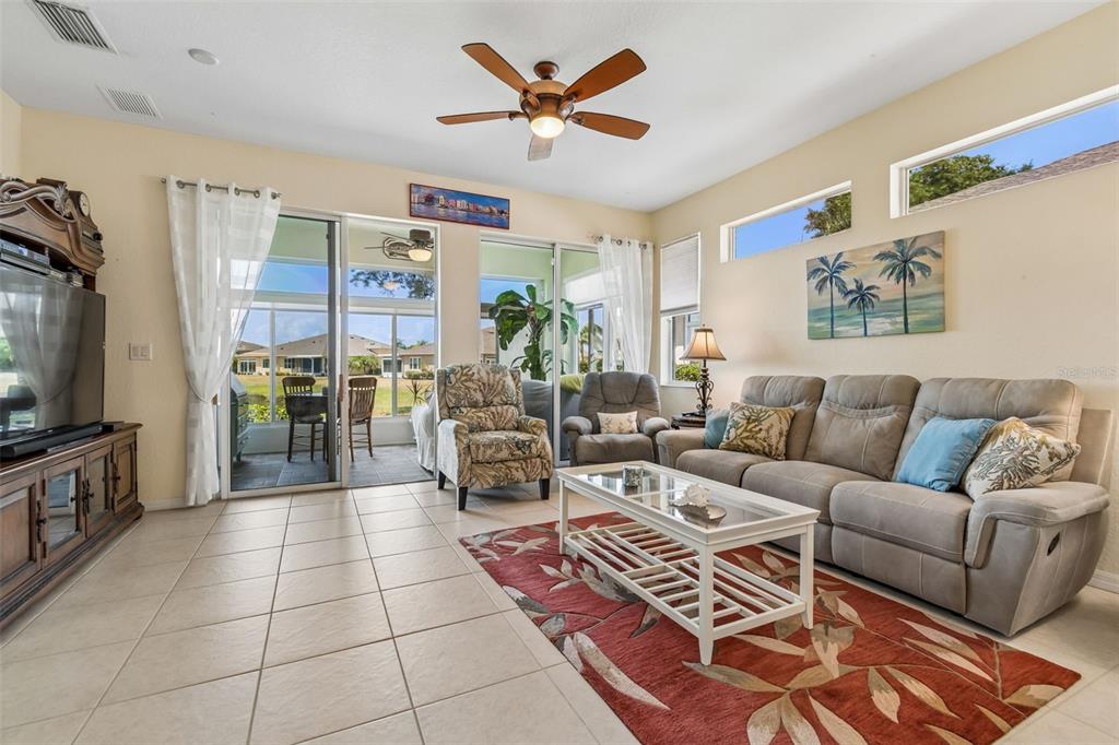 A living room features tile floors, a ceiling fan, a sofa, and sliding glass doors — 2011 SIFIELD GREENS WAY UNIT 71, SUN CITY CENTER, FL