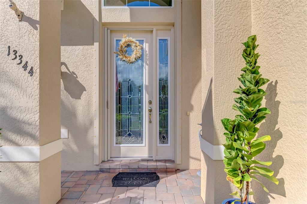 A front entryway features a glass-paneled door, a welcome mat, and a potted plant — 13344 CREEKSIDE LANE, PORT CHARLOTTE, FL