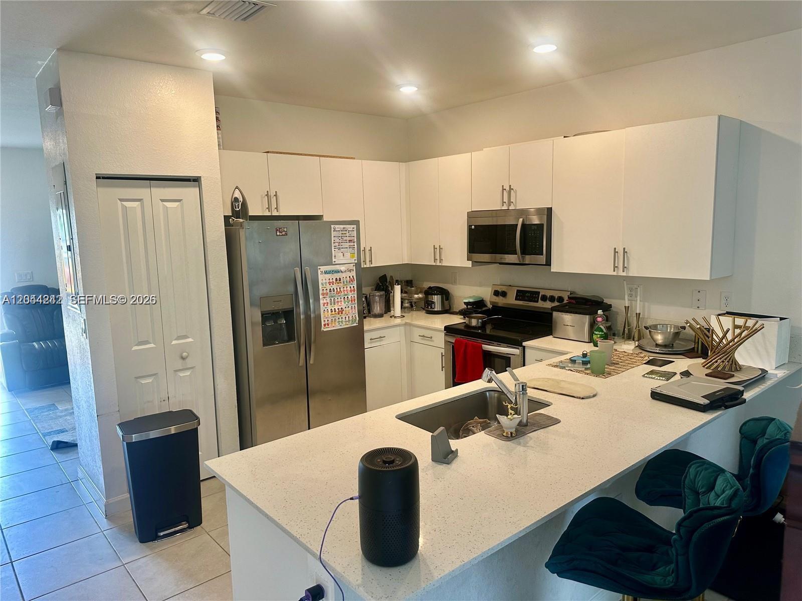 A kitchen features white cabinets, stainless steel appliances, and a white quartz breakfast bar — 22913 SW 99th Ave, Cutler Bay FL 33190, CUTLER BAY, FL