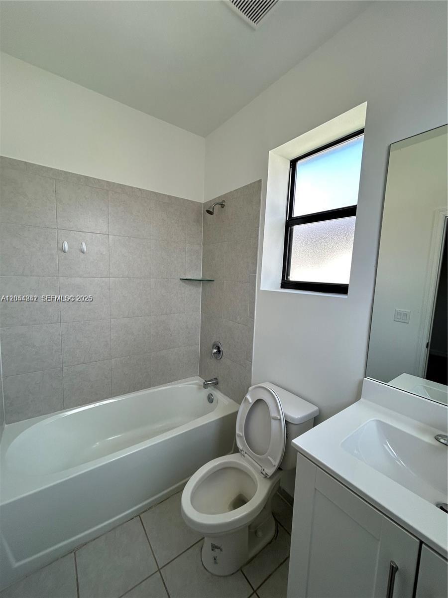 A bathroom features a white bathtub with tiled walls, a toilet, and a vanity mirror — 22913 SW 99th Ave, Cutler Bay FL 33190, CUTLER BAY, FL