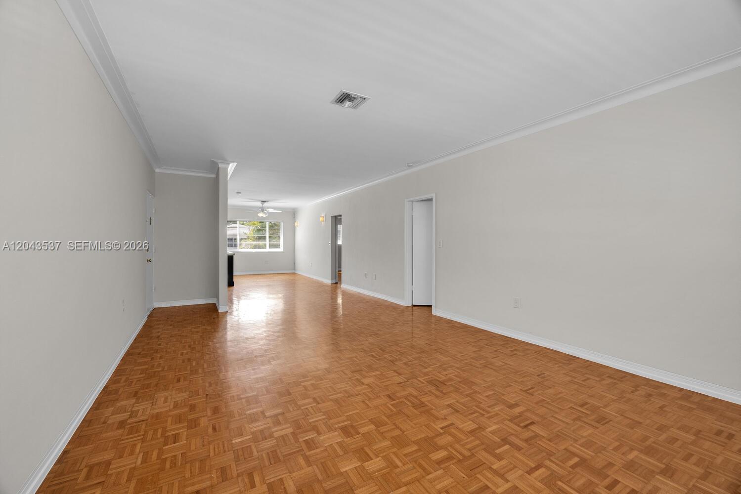 An empty room features light-colored walls, crown molding, and a parquet wood floor — 940 Sevilla Ave # 206, Coral Gables FL 33134, CORAL GABLES, FL