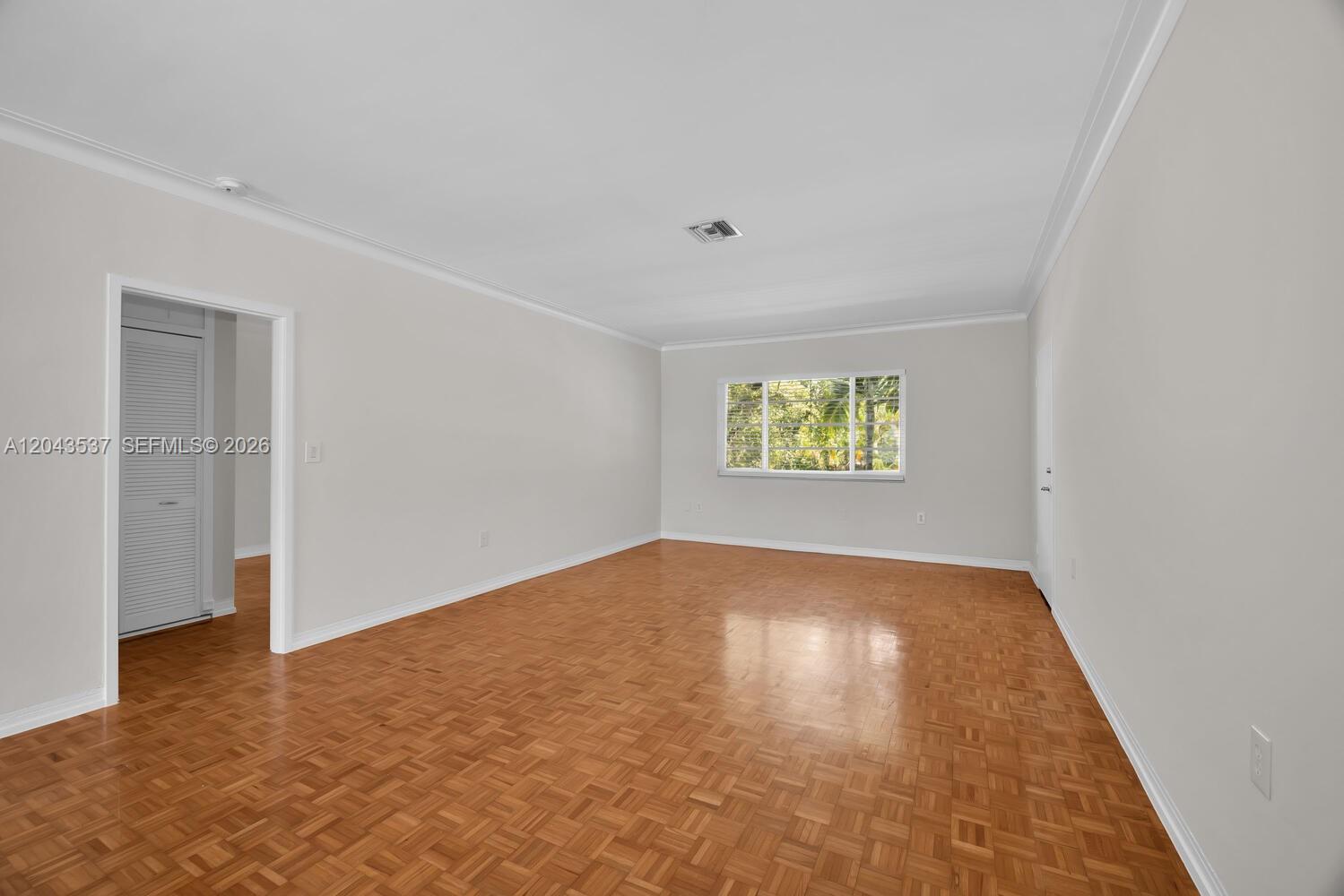 An empty room features light gray walls, crown molding, and a parquet wood floor — 940 Sevilla Ave # 206, Coral Gables FL 33134, CORAL GABLES, FL