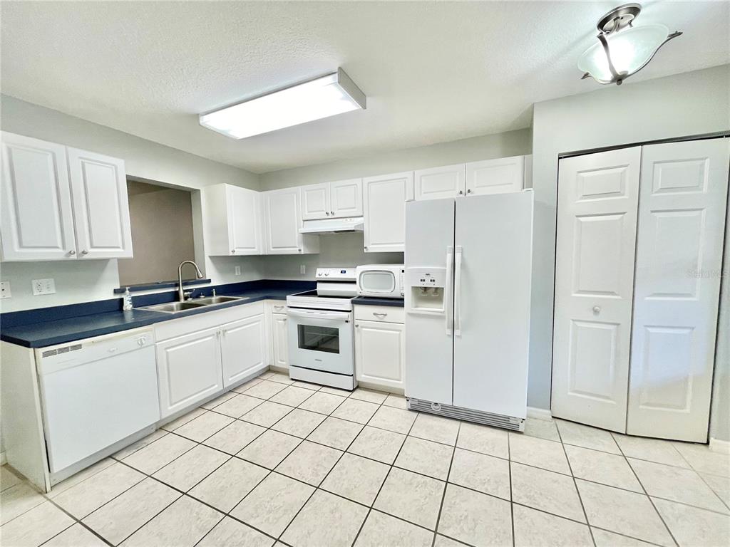 A kitchen features white cabinets, blue countertops, white appliances, and light-colored tile flooring — 2348 SW 42ND DRIVE UNIT 151, GAINESVILLE, FL