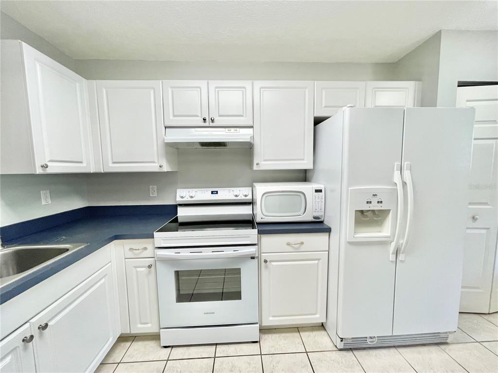 A kitchen with white cabinets, a white stove, a white refrigerator, and blue countertops — 2348 SW 42ND DRIVE UNIT 151, GAINESVILLE, FL