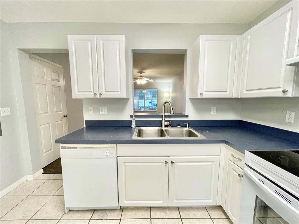 A kitchen features white cabinets, a blue countertop, a double sink, and white appliances — 2348 SW 42ND DRIVE UNIT 151, GAINESVILLE, FL