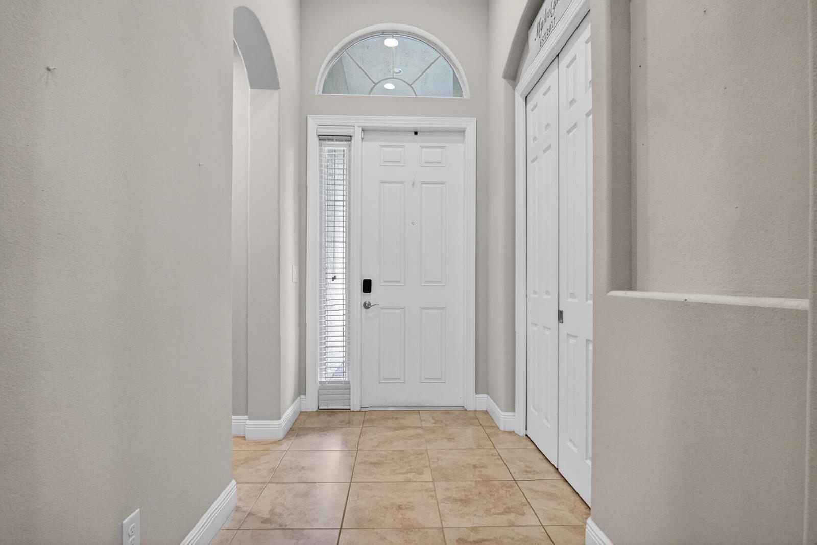 An entryway features a white front door with a sidelight, tile flooring, and a closet — 9531 Shadow Lane, Fort Pierce FL 34951, FORT PIERCE, FL