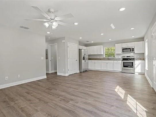 An open-concept kitchen and living area with light gray walls and wood-look flooring — 800 WARE AVENUE NE, WINTER HAVEN, FL