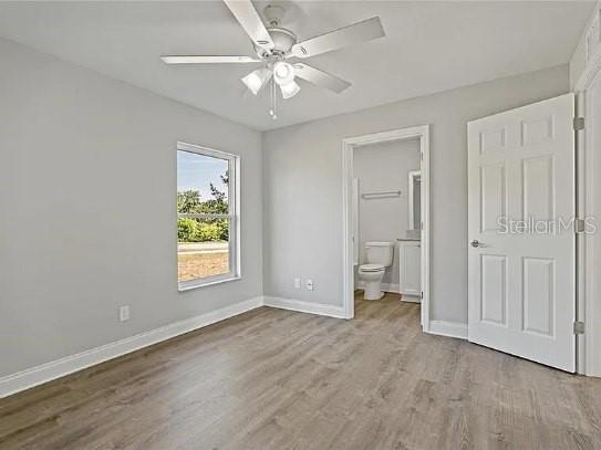 A bedroom with light gray walls, wood-look flooring, a ceiling fan, and an attached bathroom — 800 WARE AVENUE NE, WINTER HAVEN, FL