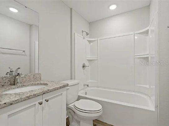 A bathroom with a white vanity, granite countertop, toilet, and a tub-shower combination — 800 WARE AVENUE NE, WINTER HAVEN, FL